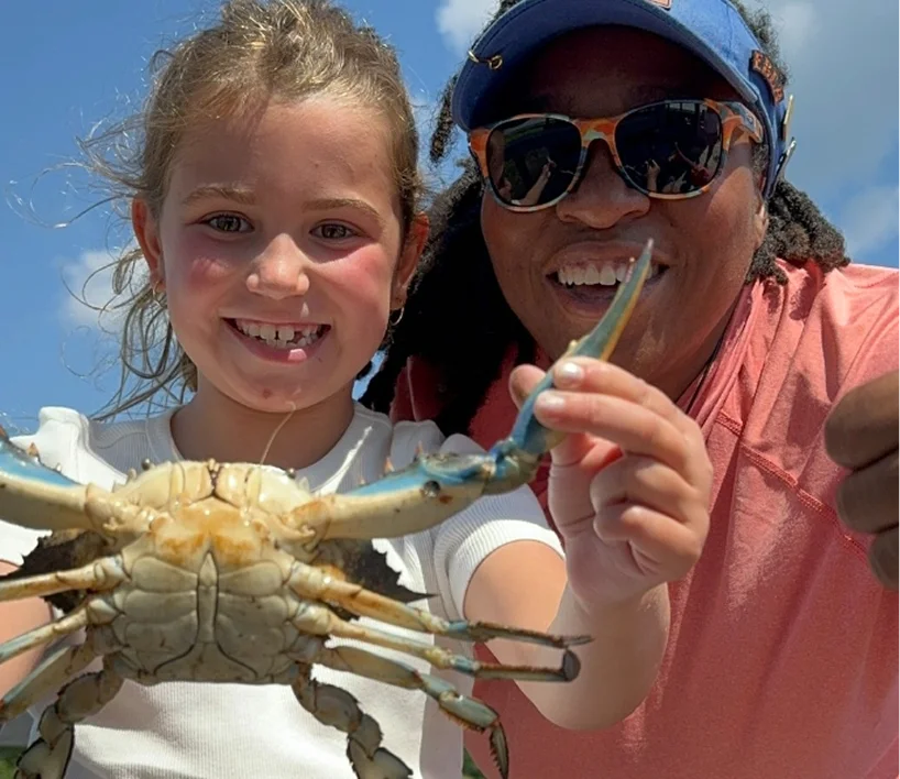 a woman and a girl holding a crab